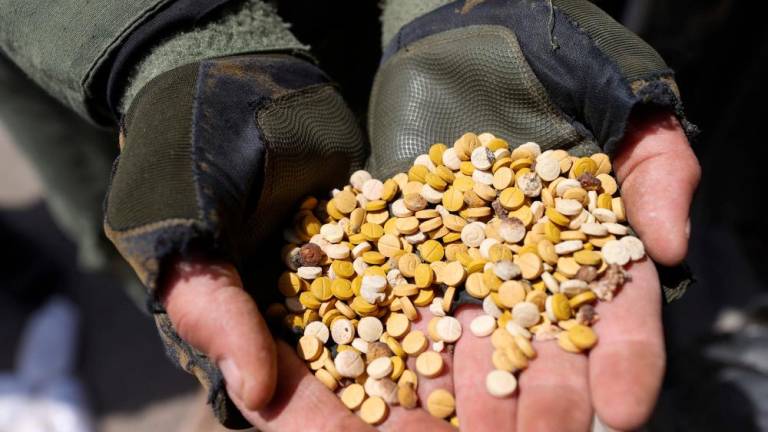 In this file photo taken on April 10, 2022 fighters affiliated with Syria’s “Hayat Tahrir al-Sham” (HTS) rebel-group display drugs previously seized at a checkpoint they control in Daret Ezza, in the western countryside of the northern Aleppo province. AFPPIX